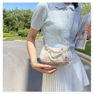 Detail of floral embroidery and vintage newspaper print on a white crossbody bag