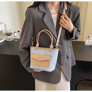 Détail du sac seau en denim bleu et cuir beige avec poignée à motif nœud torsadé