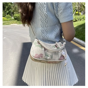 Floral embroidery detail on a small white crossbody bag with silver chain and bead accent