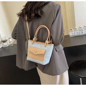Détail du sac seau en denim bleu avec garniture en cuir kaki et bandoulière réglable