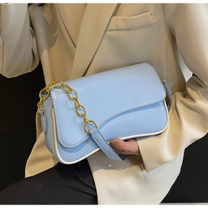 Detail der hellblauen Satteltasche mit goldener Kette und weißen Kontrastnähten am Rand