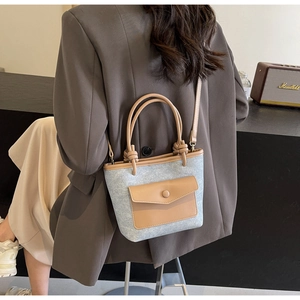 Détail du tissu texturé gris et de la poche en cuir marron du sac seau
