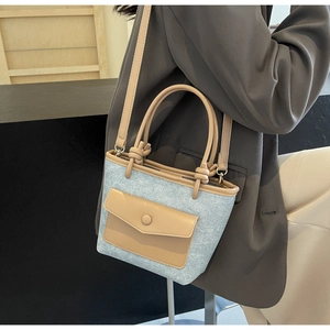 Détail d'un sac seau en denim avec garniture en cuir kaki et poignée nouée