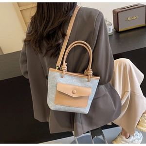 Détail du sac seau en denim avec bordure en cuir marron et poignée à nœud élégante