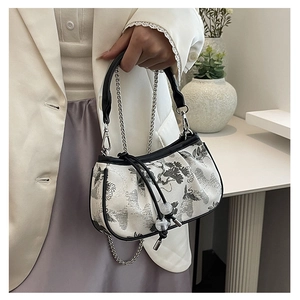 Detail of embroidered landscape handbag with black leather handle and silver chain strap