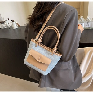 Détail du sac seau en denim bleu avec bordure en cuir kaki et poignée nouée