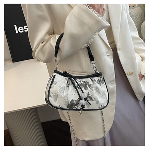 Detail of white square bag with black floral embroidery and silver metal chain strap