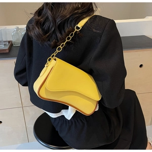 Details der gelben Umhängetasche mit asymmetrischer Klappe und goldener Kette