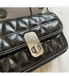 Detail of glossy black quilted leather shoulder bag with silver rectangle twist lock