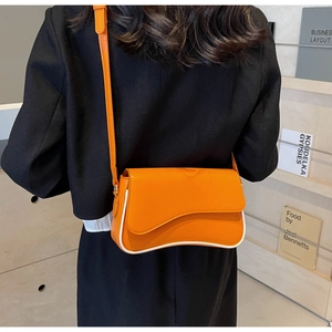 Detailansicht der orangefarbenen Ledertasche mit weißem Rand am Model