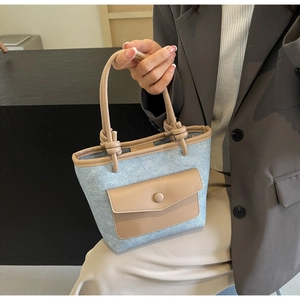 Détails du sac seau en denim bleu avec une poignée en cuir camel et nœuds design
