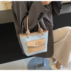 Détail du sac seau en denim bleu clair avec poignées en cuir et nœuds décoratifs
