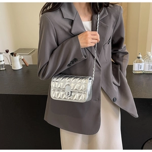 Close-up of silver quilted crossbody bag with metal chain strap and twist lock detail