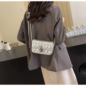 Detailed view of silver quilted crossbody bag with metal chain strap and turn-lock closure