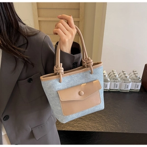 Détail du sac seau en denim bleu clair et cuir marron avec poignée à nœuds décoratifs
