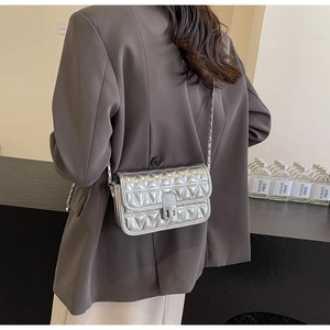 Silver quilted chain bag with rotating buckle and metallic finish shown on model back