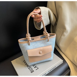 Détail du sac seau en denim bleu clair avec garniture en cuir beige et anse nouée