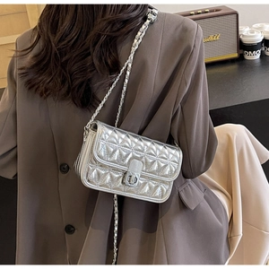 Silver metallic quilted chain crossbody bag with square metal lock shown on a model