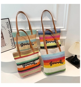 Detail of colorful striped straw tote bag featuring Summer embroidery and leather straps