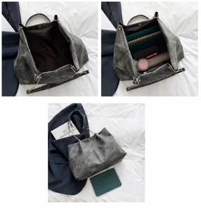 Detalle del interior espacioso de la bolsa tote gris con correa de cadena y accesorios