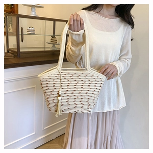 Detail of cream cotton rope woven tote bag with brown geometric patterns and tassel charm