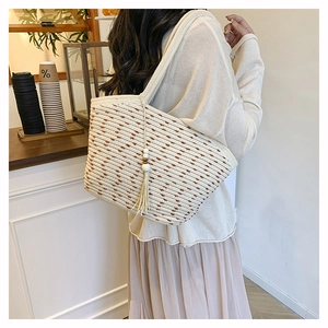 Detail of woven straw tote bag with brown stripes and decorative tassel in a cafe setting