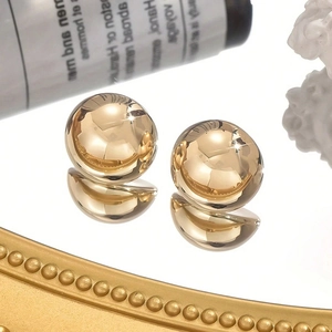 Polished 18K gold plated ball stud earrings with mirror finish on a decorative tray