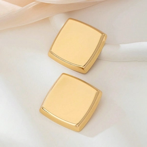 Minimalist square gold stud earrings with a polished mirror finish on white silk fabric