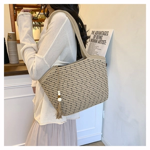 Detailed texture of beige woven tote bag with black dots and decorative wood bead tassel