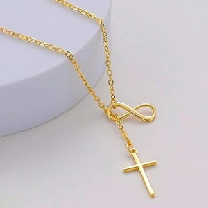 Collana dorata con ciondolo infinito e croce su piedistallo bianco per uno stile minimale