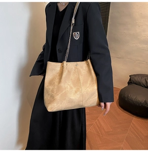 Primer plano de un bolso tote marrón con textura vintage y correa de cadena en una modelo