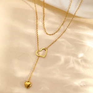 Elegant gold double-layered heart pendant long necklace on a minimalist silk background