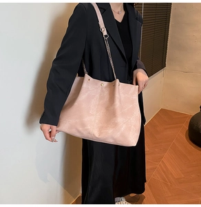 Detalle de bolso rosa con textura de mármol y cadena dorada sobre blazer negro