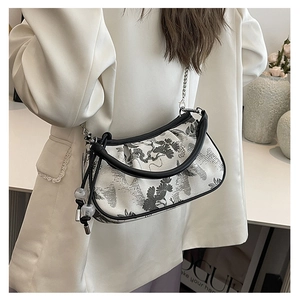 Detail of a half-moon shoulder bag featuring traditional landscape embroidery and metal chain