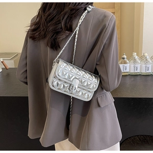 Rear view of silver quilted chain bag worn by model showing modern metallic texture