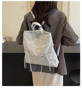 Close-up of metallic silver backpack featuring wrinkled texture and ribbon bow details