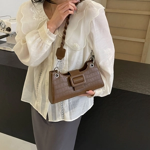Brown crocodile-embossed baguette bag with oversized buckle and braided shoulder strap