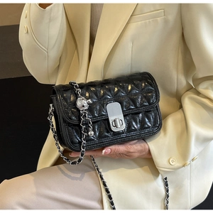 Detail of black quilted leather crossbody bag with silver chain and metal ball charm