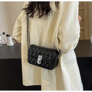 Detail of black quilted leather shoulder bag with silver chain strap and metal lock