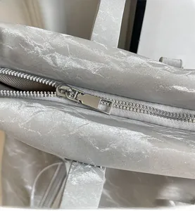 Detailed macro view of the smooth silver metallic zipper on the crinkled fabric bag