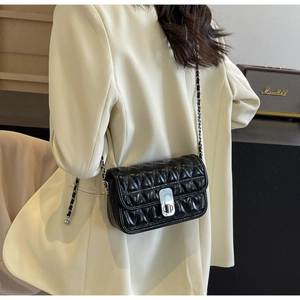 Detail of black quilted leather shoulder bag with silver turn-lock and chain strap