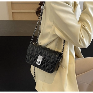 Detail of black quilted patent leather bag with silver chain and metal twist lock