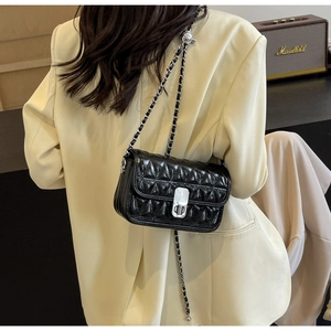 Detail of black quilted leather shoulder bag with silver turn-lock and chain strap