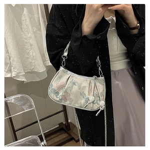 Detailed macro of embroidered floral jacquard fabric on a white square bag with metal chain