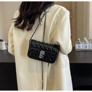 Detailed view of a black quilted leather bag with a silver swivel lock and chain strap