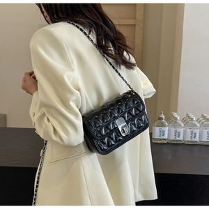 Detail of black quilted leather shoulder bag with silver chain strap and metal clasp