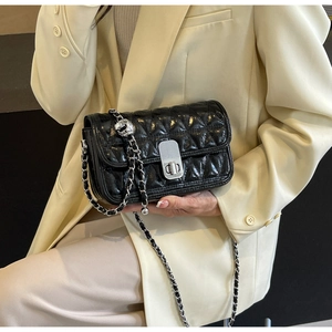 Detail of black quilted leather shoulder bag with silver chain strap and metal clasp