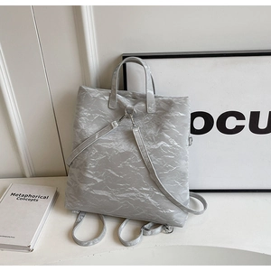 Detail of light grey wrinkled fabric texture and silver hardware on a versatile backpack