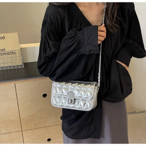 Silver quilted chain bag shown on model featuring metallic finish and turn-lock closure