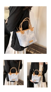 Detail of blue marble pattern bucket bag with brown leather handles and brand tag